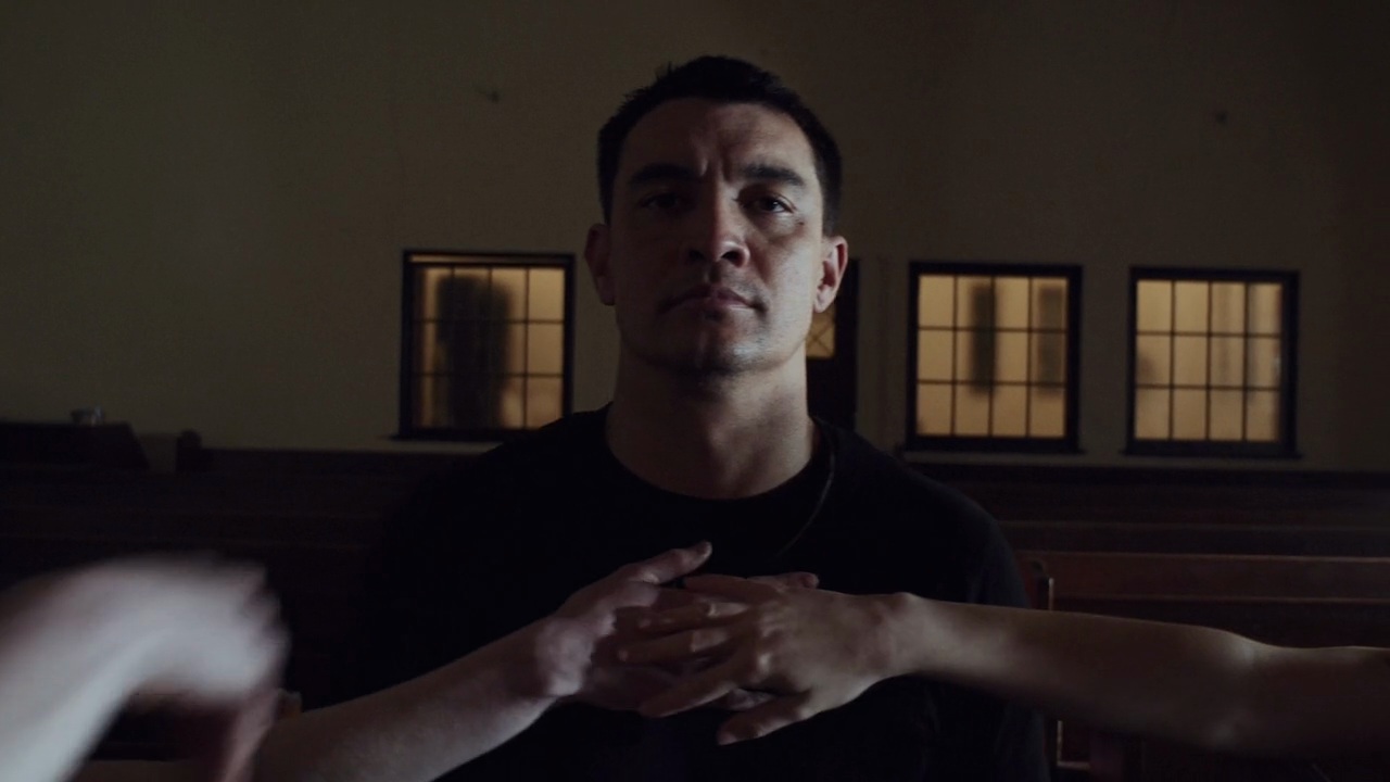Hands reaching from the pews around a seated man in Rock Bottom