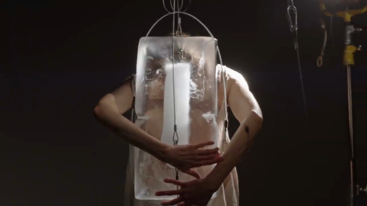 Corina Kinnear embracing a suspended block of ice in The Time Has Come
